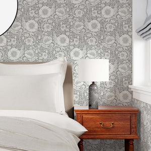 Bedroom with floral wallpaper, wooden nightstand, and lamp.