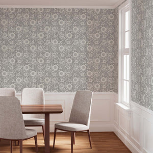 Dining room with floral wallpaper, wooden table, and gray chairs.