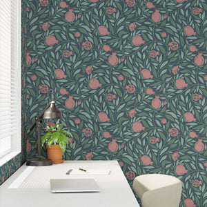 Woodcut Pomegranate fruit and leaves on dark teal background closeup in a desk nook